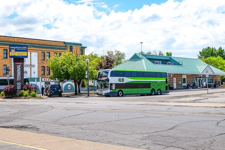 green bus at bus station in niagara falls with roadway in front.