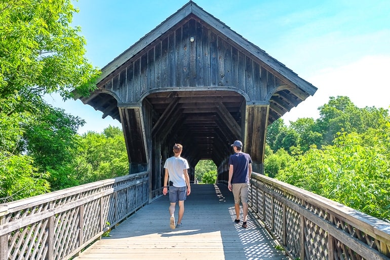 two guys crossing wooden covered bridge in guelph ontario.