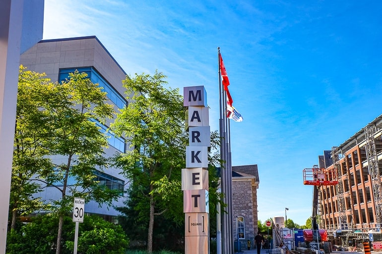 metallic sign for market with flag poles behind.