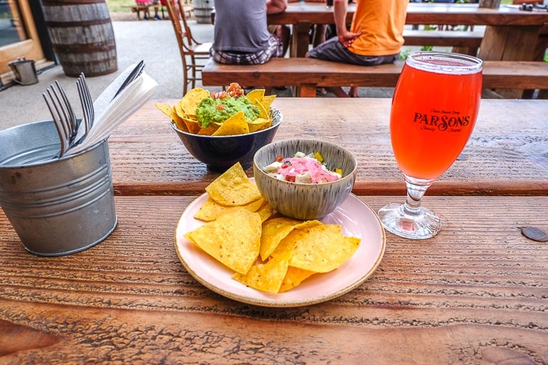 chips and salsa on plate with pint of beer on wooden table.