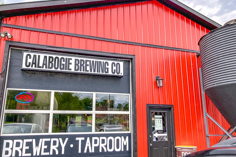 red barn with garage door and brewery sign in front.