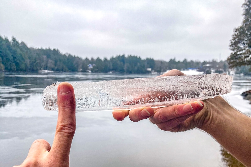 piece of thin ice held in air with hand in front.